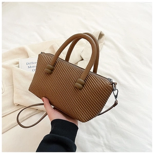 Détails de la texture en cuir tressé marron et des poignées de ce sac à main épuré