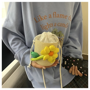 Detail van mini stro emmer tas met gele bloem en witte trekkoordsluiting voor strandvakantie