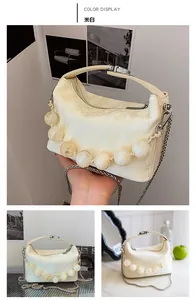 Detail van gebroken witte geplooide leren crossbodytas met grote kralen en zilveren ketting