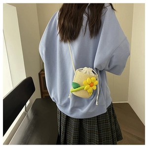 Detail view of mini straw bucket bag with sunflower accent and white drawstring closure