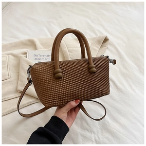 Détail du sac bandoulière marron caramel avec texture tressée et boucles argentées