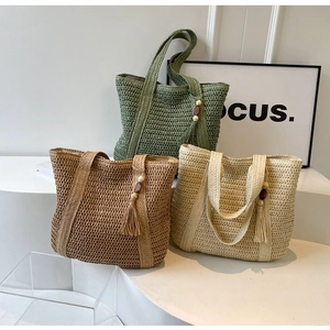 Close-up of woven straw tote bags with decorative tassels and wooden beads detail