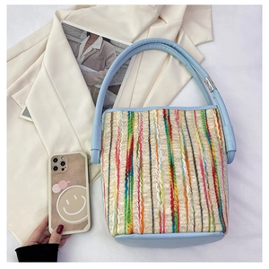 Détail du sac seau tissé coloré avec finitions en cuir bleu et rayures vives