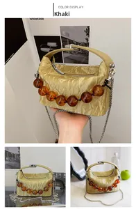 Detail van khaki tas met handvat van barnsteen kralen en metalen ketting schouderband