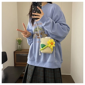 Straw mini bucket bag with yellow flower charm and drawstring closure detail
