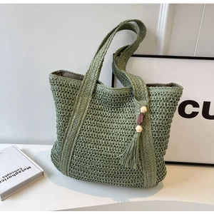 Close-up of grass green woven tote bag with detailed hollow weave and tassel charm