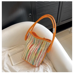 Détail du sac cabas tissé à rayures colorées avec poignée orange et boucle métal