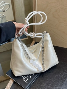 Chic cream hobo shoulder bag with beaded chain and knotted strap on book decor