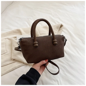 Vue détaillée de la texture gaufrée marron foncé sur un sac boston décontracté