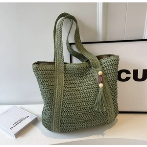 Detail of green woven tote bag with hollow mesh pattern and beaded tassel charm