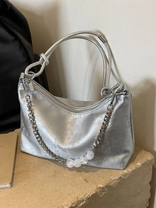 Silver metallic Hobo underarm bag with floral texture and beaded chain strap on stone