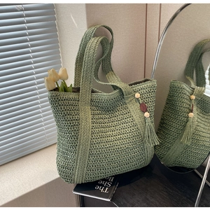 Close-up of green woven tote bag with shell tassels and wooden beads detail