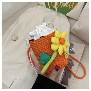Close-up of woven orange bucket bag featuring a yellow sunflower and drawstring closure