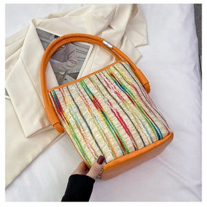Détail du sac cabas tissé à rayures avec poignées rondes en cuir orange et accents argentés