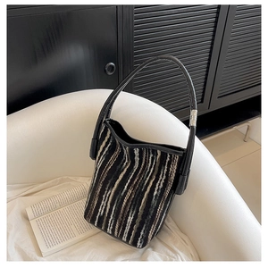 Gros plan du sac seau en tricot avec rayures verticales et anse en cuir haut de gamme