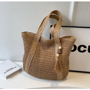 Close-up of woven hollow mesh straw tote with bohemian tassel and wooden bead detail
