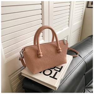 Detailed view of pink crossbody bag with quilted texture and ball knot handle design