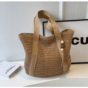Detail of hand-woven straw tote bag featuring decorative wooden beads and a natural texture