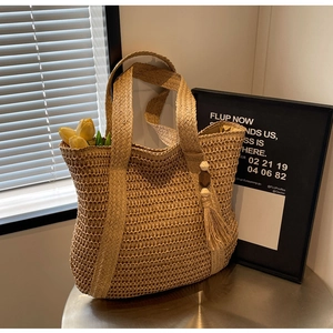 Detailed close-up of handmade straw tote bag with beaded tassels and natural texture