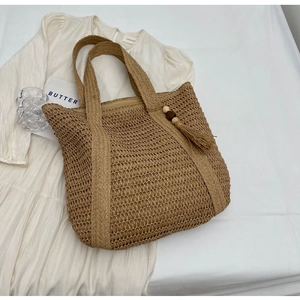Detail of hand-woven straw tote with wooden bead tassels and inner zipper lining