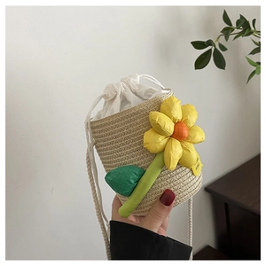 Detail of straw bucket bag with sunflower 3D floral accent and drawstring closure