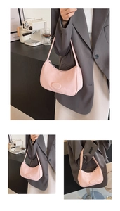 Dettaglio borsa a mezzaluna in camoscio rosa con logo e design minimalista sottospalla