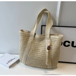 Detailed close-up of handmade woven straw tote bag with decorative purple wood bead tassel