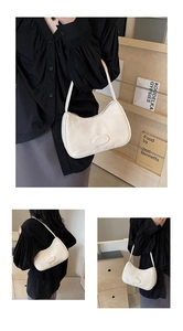 Dettaglio di una borsa hobo in pelle beige crema indossata a spalla con logo e trama fine