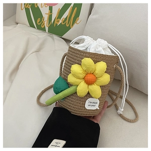 Detail of a straw bucket bag with yellow floral decor and white drawstring closure
