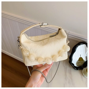 Detail van de roomwitte crossbodytas met grote sierparels en een metalen ketting