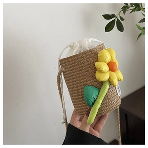 Macro view of woven straw bucket bag with yellow sunflower and drawstring liner