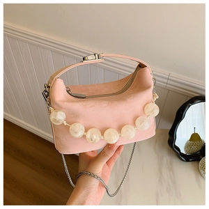 Detail van roze suède crossbodytas met decoratieve grote doorschijnende kralen