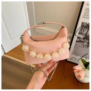 Detail van roze hobo tas met grote crème parel handgreep en zilveren kettingriem
