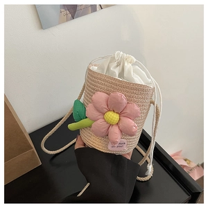 Detail of hand-woven straw bucket bag featuring a large 3D pink flower and drawstring