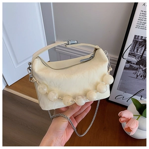 Detail van crème crossbodytas met grote harskralenketting en zilveren riem