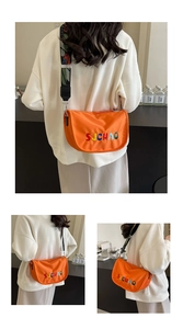 Detail of orange fabric crescent bag featuring colorful SJCHAO embroidery and wide strap