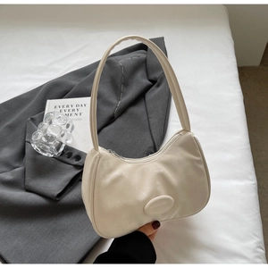 Dettaglio della borsa a spalla beige a mezzaluna con logo inciso su ecopelle liscia