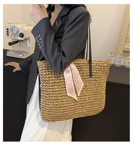 Detail of large straw woven tote with leather handles and pink heart pattern scarf