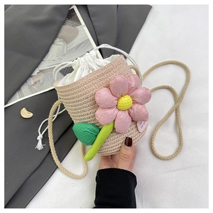 Close-up of woven straw bucket bag with 3D pink fabric flowers and drawstring liner