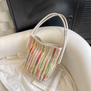 Sac fourre-tout en tricot à rayures colorées avec anses crème sur un canapé minimaliste