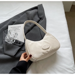 Dettaglio della borsa a mezzaluna color crema minimalista in pelle lucida con logo