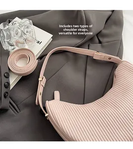 Detail of pink pleated hobo bag with two detachable shoulder straps on grey suit jacket