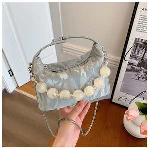 Detail van zilverblauwe geplooide handtas met kralen handvat en zilveren ketting riem