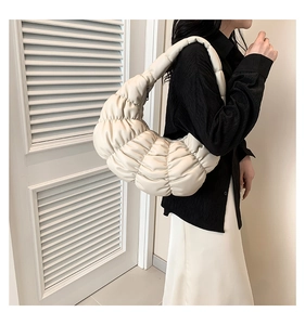 Detail shot of a white ruched cloud shoulder bag with soft quilted texture on a model