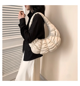 Close-up of beige ruched dumpling bag with quilted texture and soft padded shoulder strap