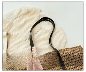 Detail of woven straw tote bag with brown leather strap and pink heart silk scarf decor