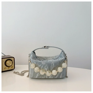Detail van lichtblauwe geplooide handtas met doorschijnend parelhandvat en zilveren ketting