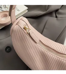 Detailed macro of pink dumpling bag with vertical pleats and golden metal zipper