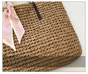 Detailed macro view of woven straw beach bag featuring a pink heart pattern silk scarf accent