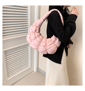 Pink pleated cloud bag shown on model's shoulder with soft aesthetic lighting